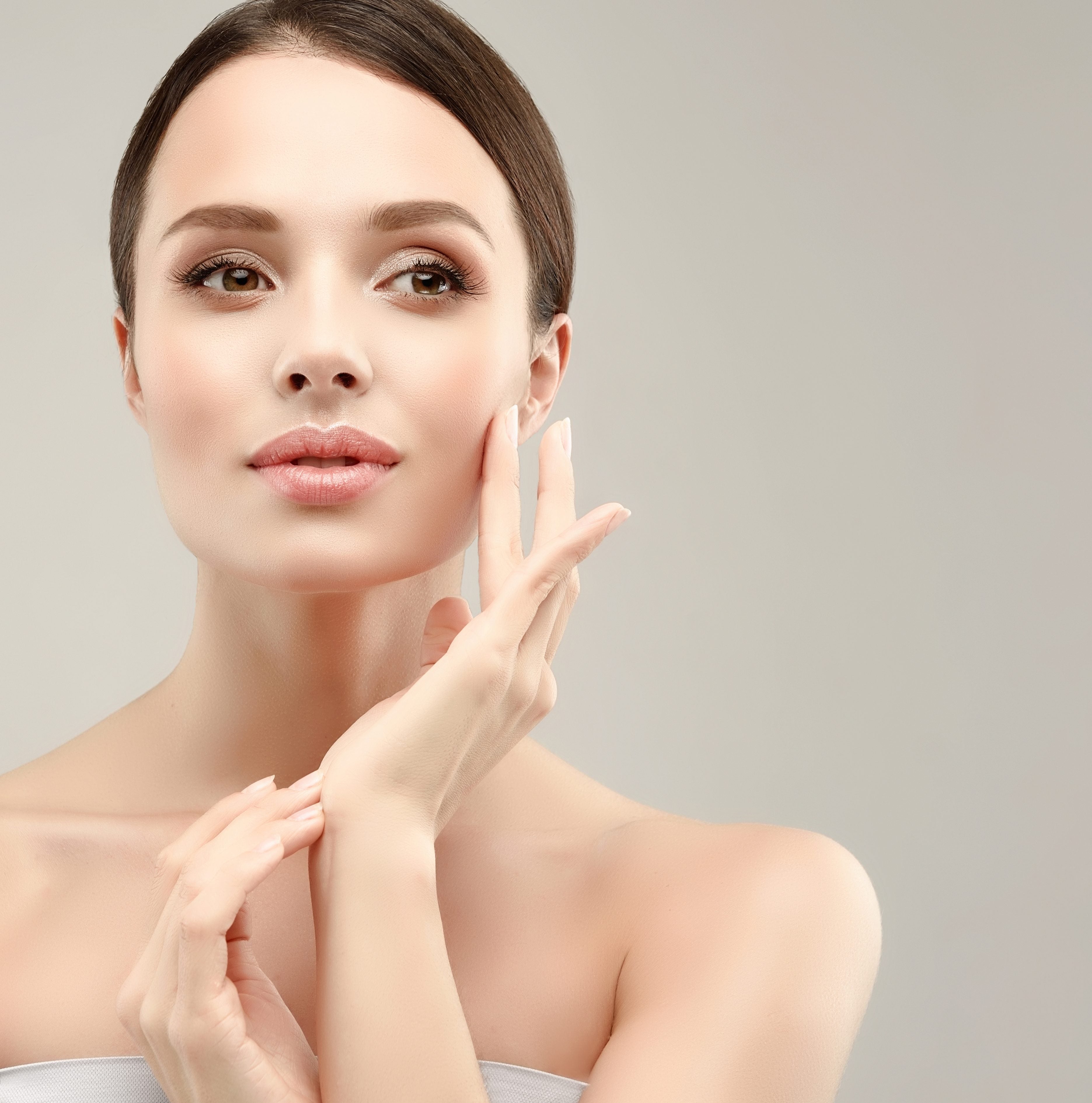 Gorgeous, young woman with clean, fresh skin is touching own face. Cosmetology.